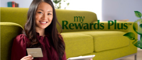 Lady sitting on the floor in front of the couch with her debit card checking her reward plus points